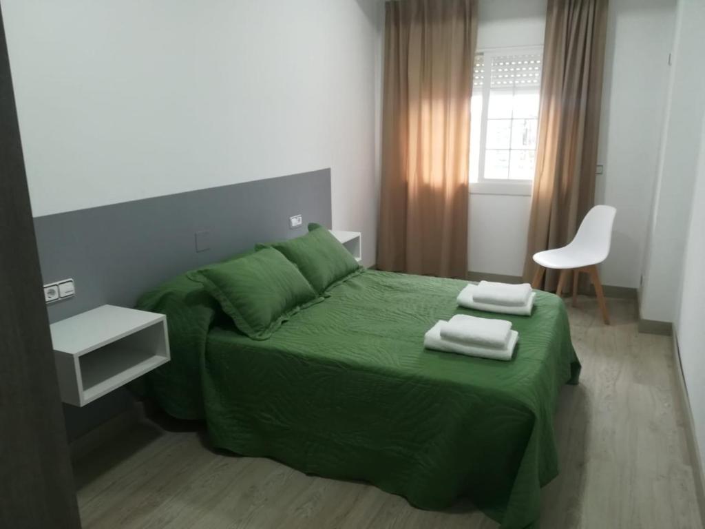 a bedroom with a green bed with two towels on it at HORIZON in Arzúa