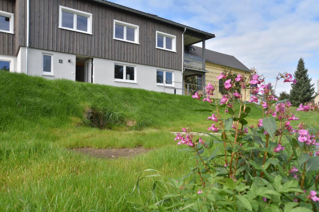 a house on the side of a hill with pink flowers at Ferienwohnung Spreeblick in Alter Graben