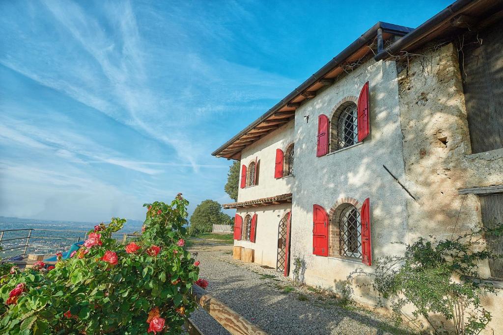 an old building with red doors and flowers on a hill at Rustico Costa D'oro in Farra di Soligo
