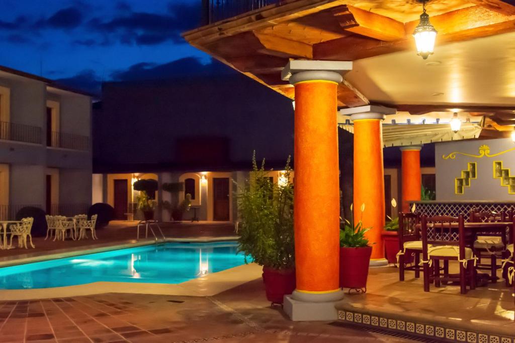 uma piscina de resort com colunas cor de laranja, mesas e cadeiras em Santa Helena Plaza em Oaxaca de Juárez