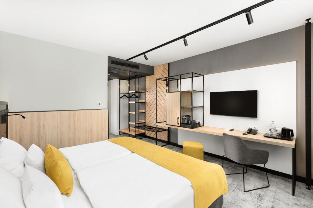 Schlafzimmer mit einem Bett, einem Schreibtisch und einem TV in der Unterkunft Art Hotel Szeged in Szeged