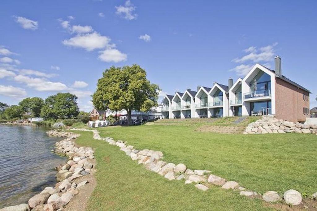 ein großes Gebäude neben einem Wasserkörper in der Unterkunft Chalet Möwenblick Rügen mit Meerblick, Sauna und Kamin in Alt Reddevitz