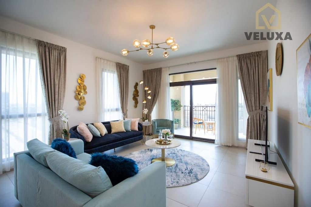Veluxa - Luxury and bright 1 bedroom apartment, Burj view! في دبي: غرفة معيشة مع أريكة وطاولة