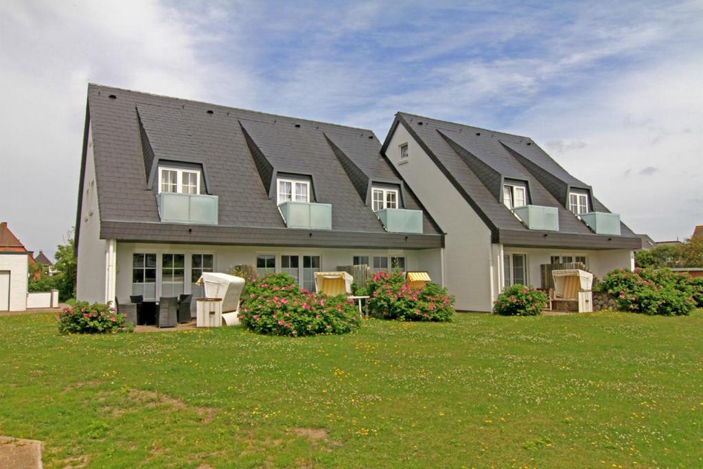 a large house with a gambrel roof on a lawn at Westbrise App 7 in Wenningstedt