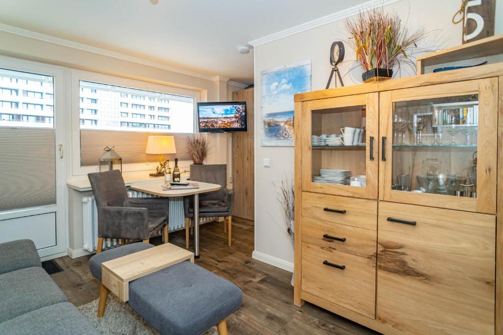 a living room with a table and a large wooden cabinet at Strandmuschel App 309 in Westerland (Sylt)