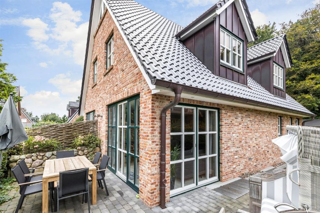 Cette maison en briques dispose d'une véranda avec une table et des chaises. dans l'établissement Anker Hus, à Westerland