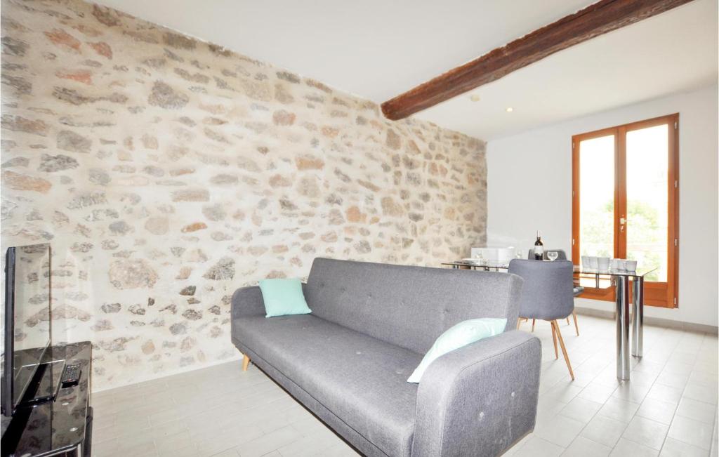 sala de estar con sofá gris y pared de piedra en Nice Apartment In Capendu With Kitchen, en Capendu