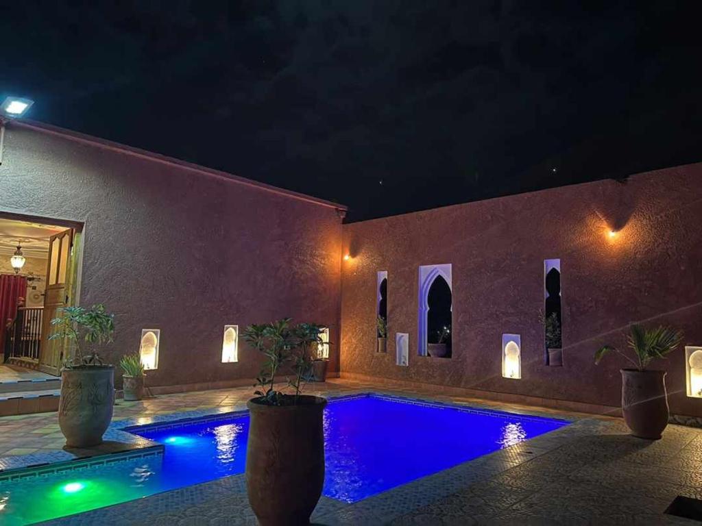 una casa con piscina por la noche en Hôtel Bia Besta en Boumalne