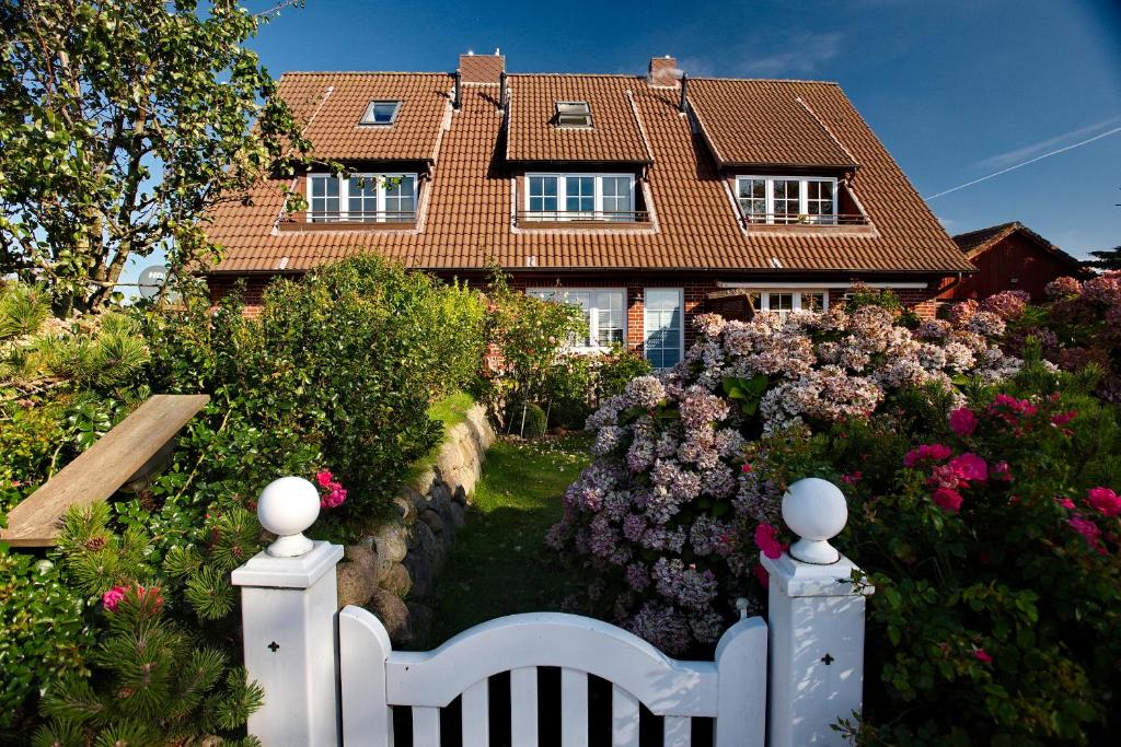 una cerca blanca frente a una casa con flores en Miekes Hüs, en Westerland