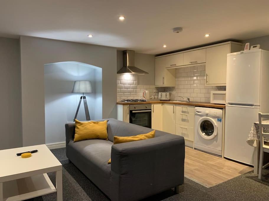 ein Wohnzimmer mit einem Sofa und einer Küche in der Unterkunft Fantastic 1 Bedroom Basement flat with free parking in Sale