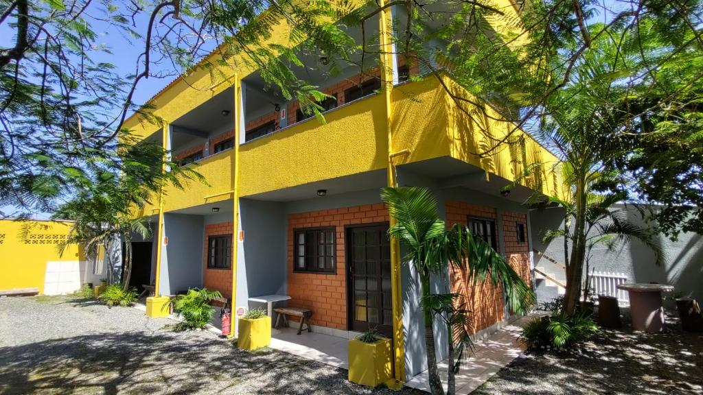 a yellow building with trees in front of it at Kantinho do Mar in São Francisco do Sul