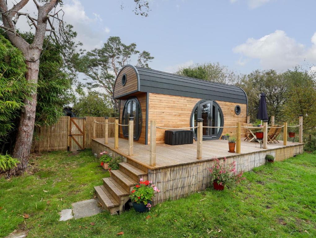 a small dog house with a deck in a yard at The Hideaway Pod in Criccieth