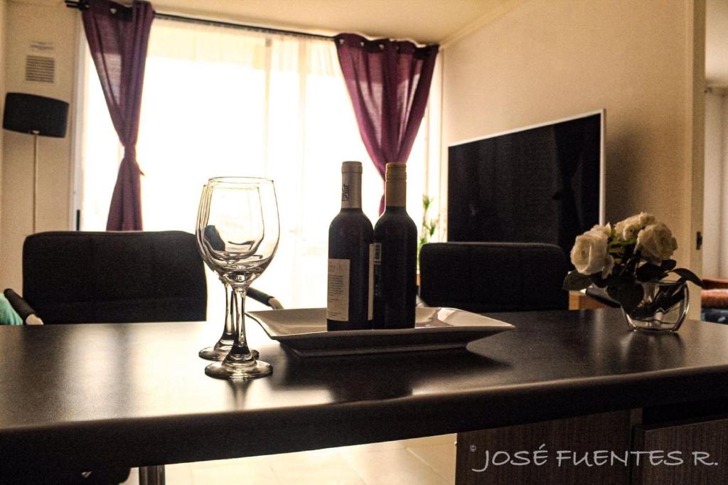 two bottles of wine on a table with a glass at Edificio Bulnes Iquique doble in Iquique