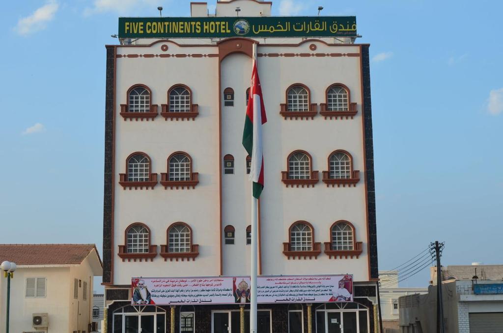Five Continents Hotel في صور: مبنى طويل مع اثنين من الأعلام أمامه