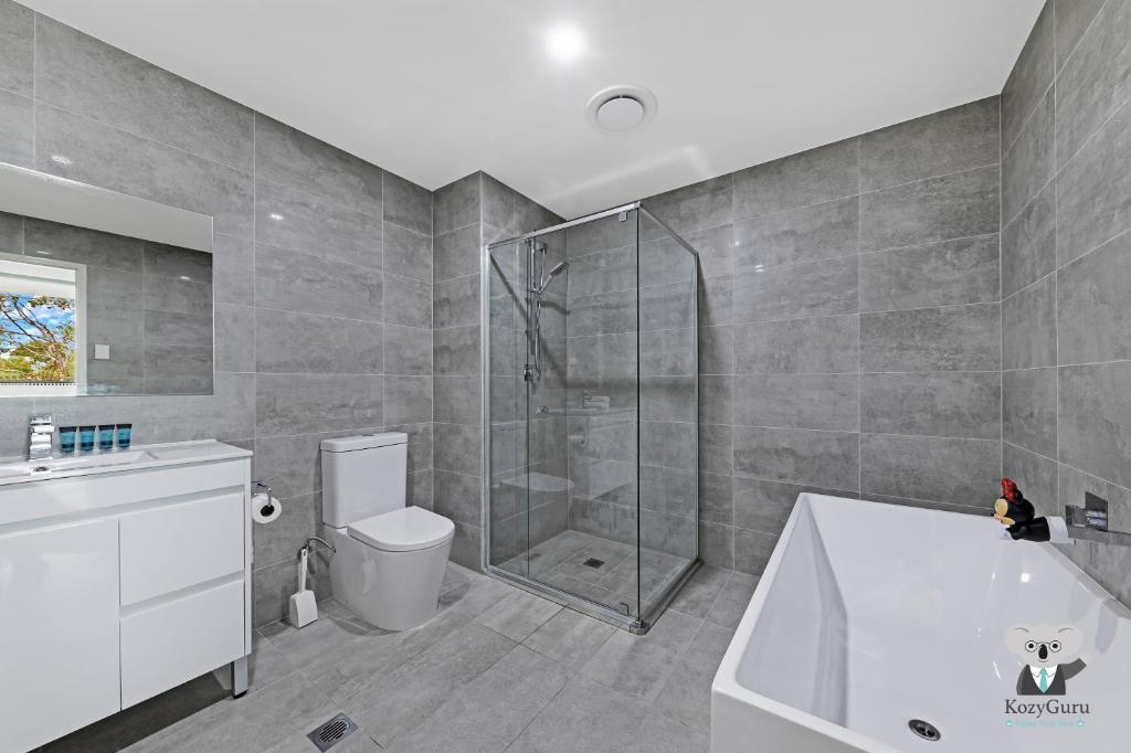 a bathroom with a shower and a tub and a toilet at KozyGuru / Wentworthville / Kozy Style 2 Bed 2 Bath APT + Free Parking NWE031A in Wentworthville