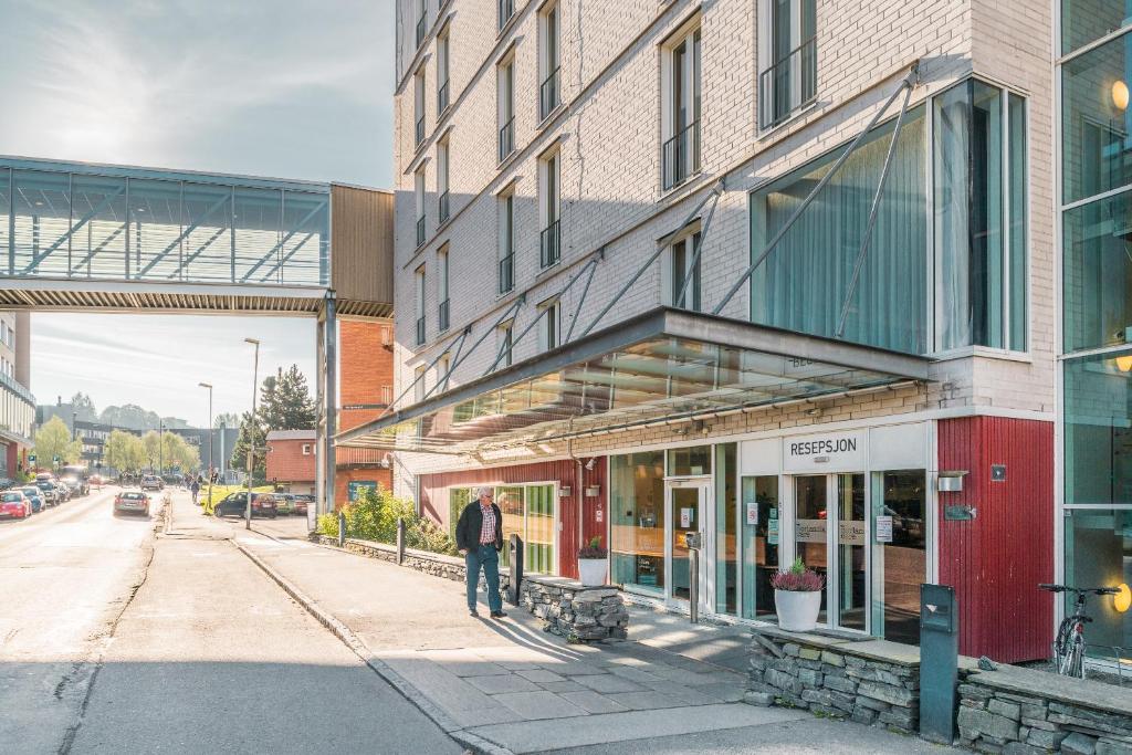 a man standing on a sidewalk in front of a building at Hotel St. Olav in Trondheim