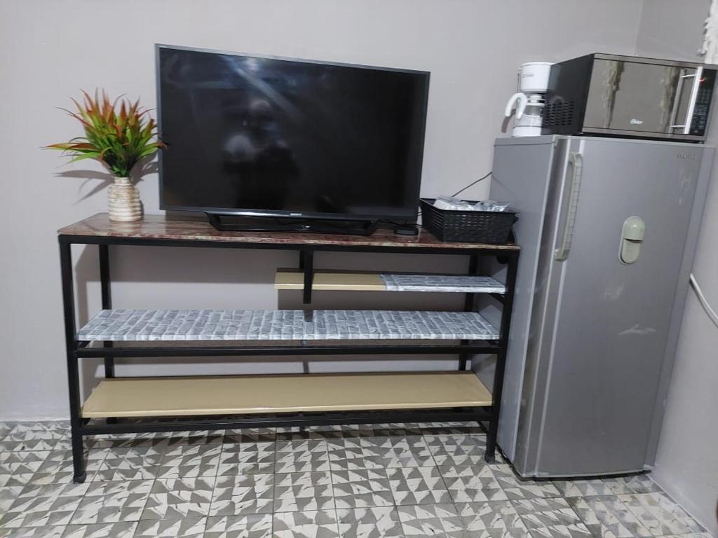 a television on a tv stand next to a refrigerator at Nirvana Hermosa habitación individual e independiente in Guatemala