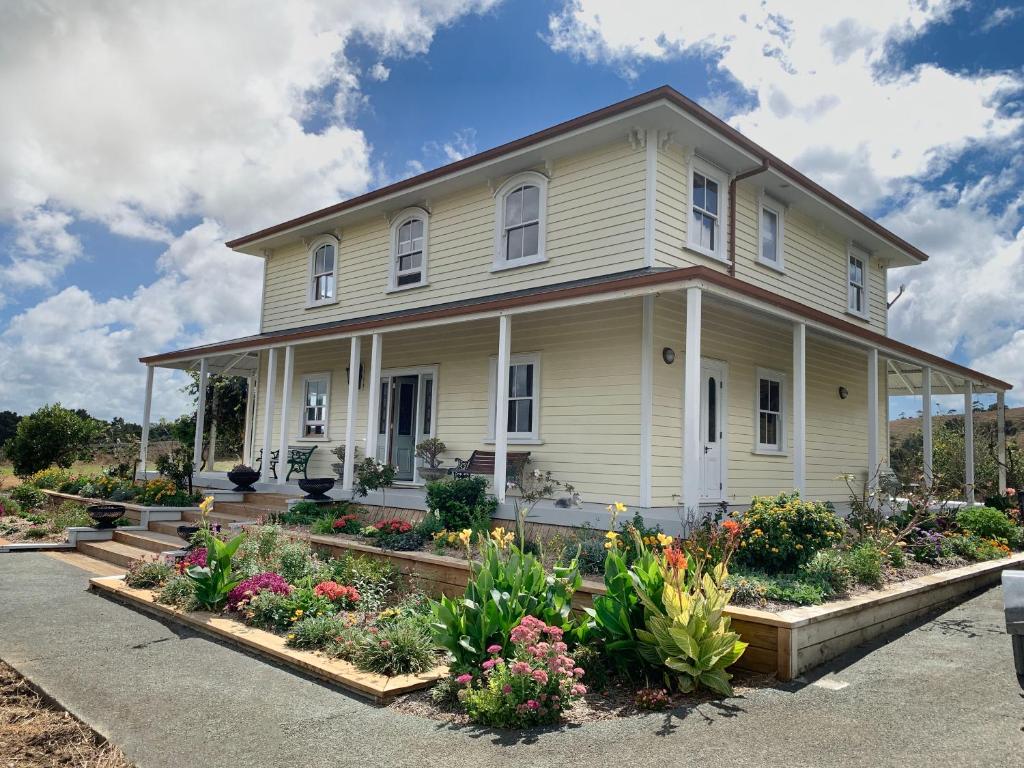 uma casa branca com flores no jardim da frente em Tracy's Boutique B&B Farmstay em Wellsford