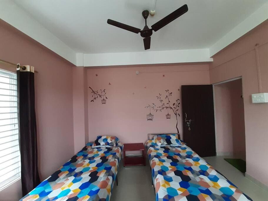 2 bedden in een kamer met een plafondventilator bij Tokari Home Stay in Guwahati