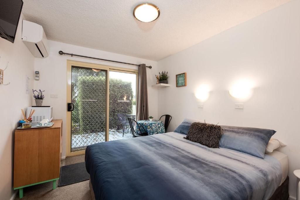 Schlafzimmer mit einem Bett und einer Glasschiebetür in der Unterkunft The Cosy Room at Arlingtons in Portarlington