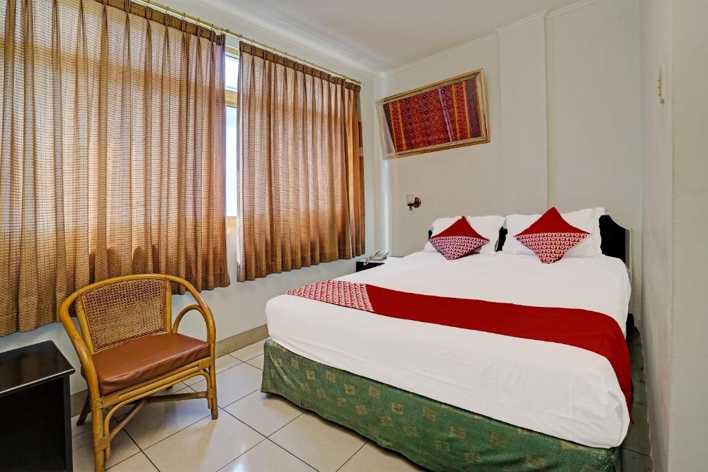 ein Schlafzimmer mit einem Bett, einem Stuhl und einem Fenster in der Unterkunft SUPER OYO 91805 Hotel Wisma Bari in Palembang