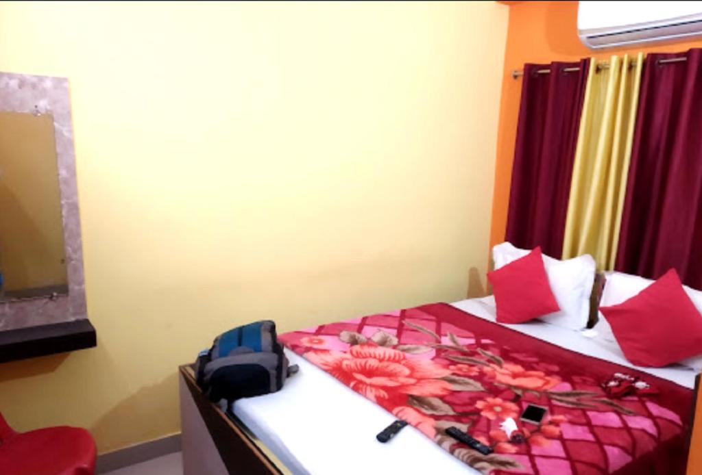 een slaapkamer met een bed met rode kussens bij Trinayani Stay - 3 min Walk to Temple in Tarapith