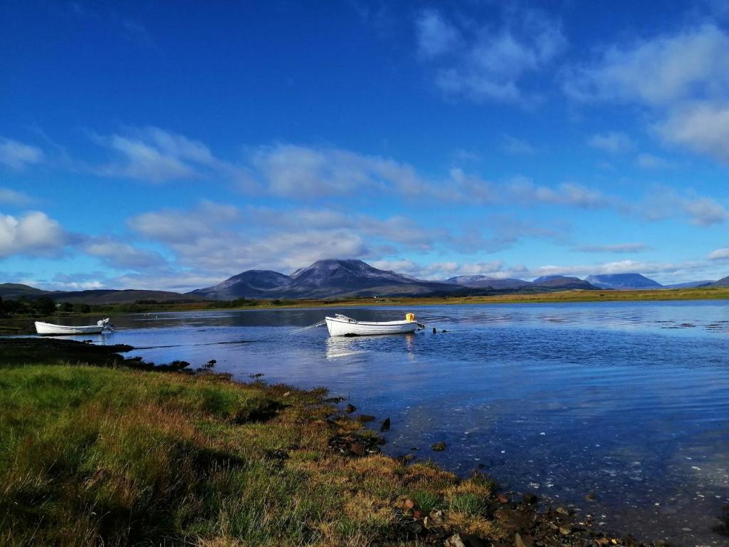 dos barcos en un lago con montañas en el fondo en Skye Coorie Cabin, en Breakish