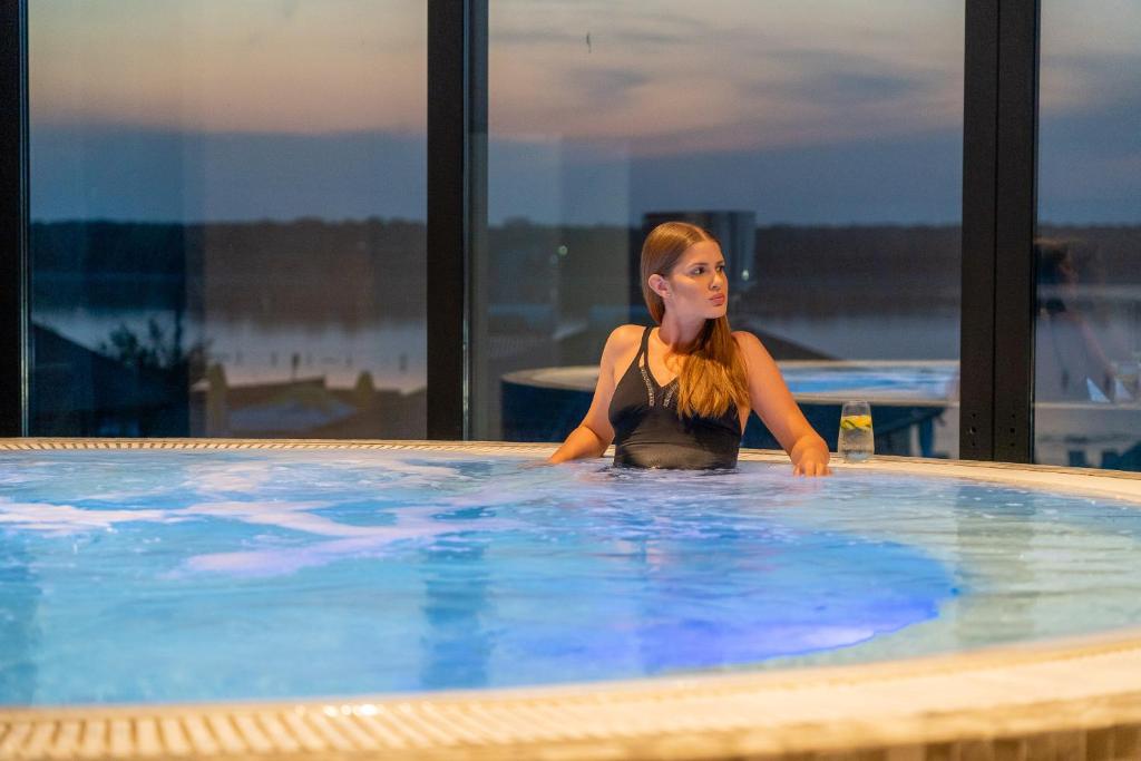 una mujer está sentada en una piscina en Alma Health & Spa Retreat, en Brăila