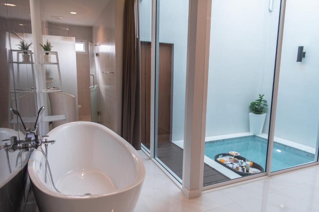 a bathroom with a tub and a shower with a swimming pool at PVILLA in Ban Phraek Sa