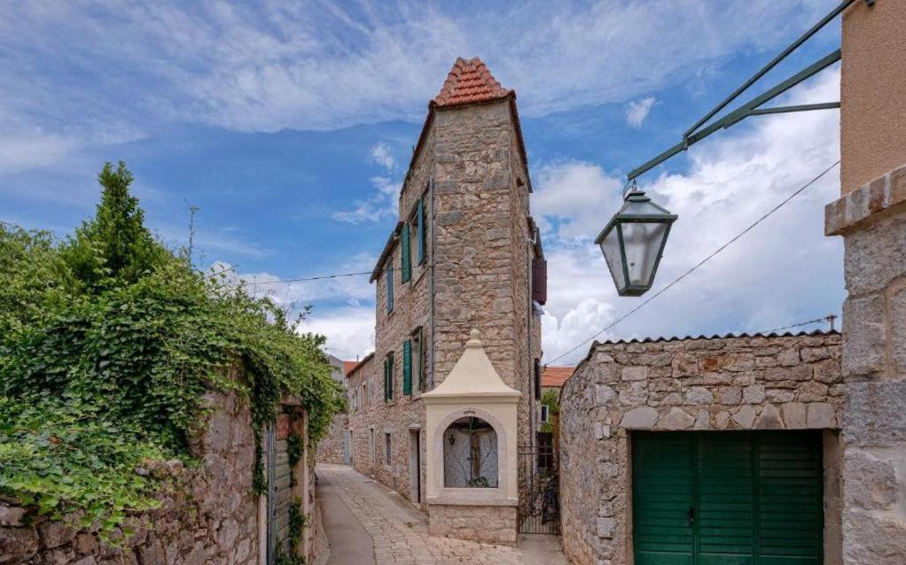 um edifício de pedra com uma porta de garagem verde e uma rua em Apartman studio Stari Grad 2 em Stari Grad