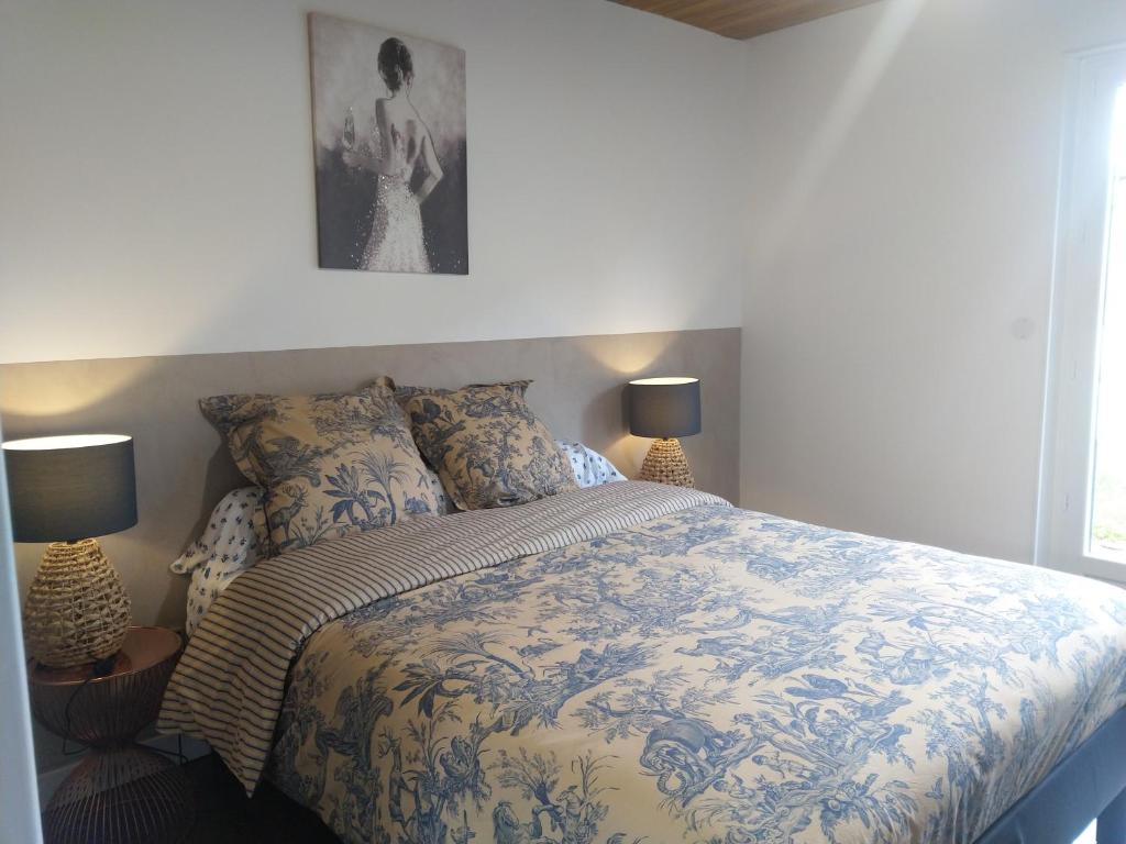 a bedroom with a bed with a blue and white comforter at Gabrielle 40m2 et terrasse in Sainte-Savine