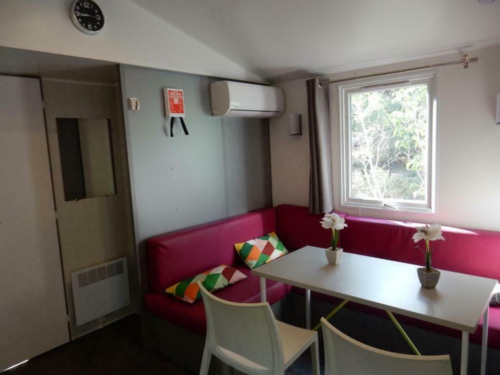 a living room with a red couch and a table at Mobile home 5-pers Camping Leï Suves-Côtes d&#39;Azur-including airco in Roquebrune-sur-Argens