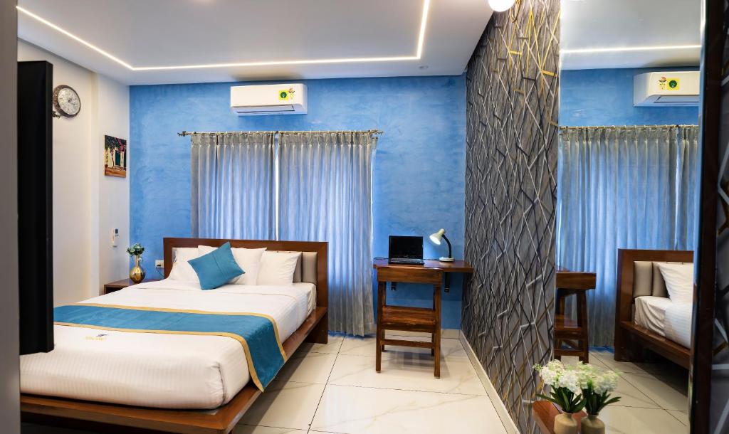 1 dormitorio con 2 camas y pared azul en Royal Tusker Luxury Service Apartments, en Mysore