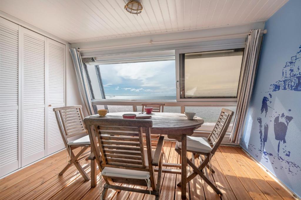 uma sala de jantar com uma mesa e cadeiras e uma janela em Vue epoustouflante sur l ocean em Pornichet