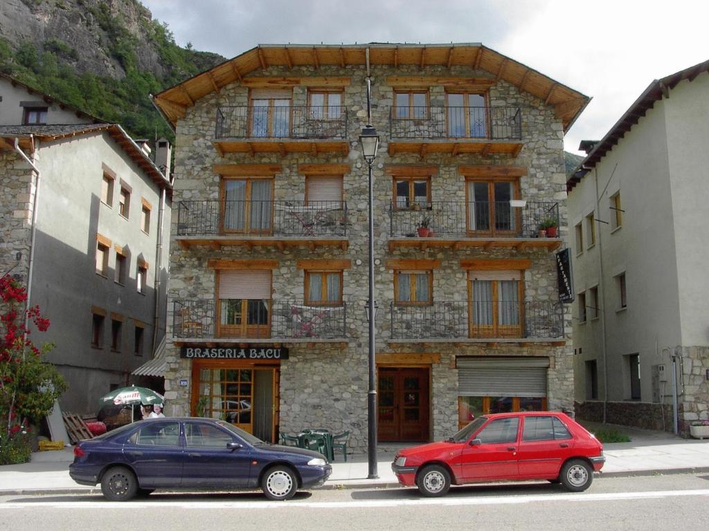 dos coches estacionados frente a un edificio de piedra en Apartaments Noray, en Barruera