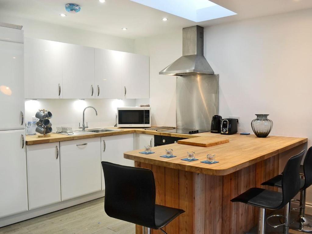 a kitchen with white cabinets and a wooden counter top at Stable Cottage in Stewarton
