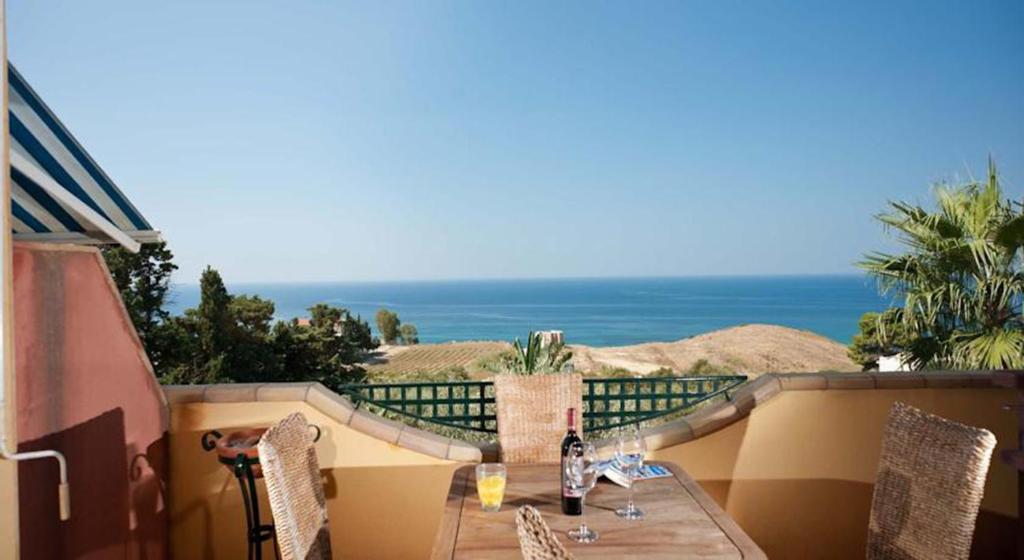 una mesa y sillas en un balcón con vistas al océano en Bono Vacanze Villa Maragani Charme & Relax, en Sciacca