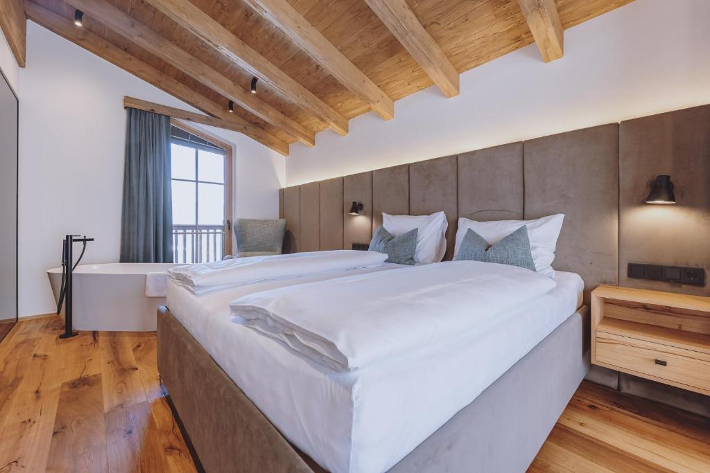 a large bedroom with a large bed and a tub at Bergdorf Hotel Zaglgut in Kaprun