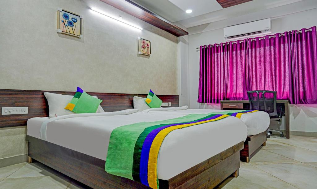 - une chambre avec un grand lit et un rideau rose dans l'établissement Treebo Trend Sai'S Urban Nest, à Vijayawada