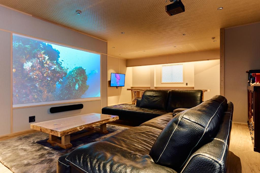 a living room with a leather couch and a large screen at Konjaku-So Tempozan Osaka Bay -Universal Bay Area- in Osaka