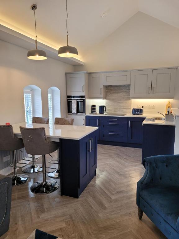 a kitchen with blue cabinets and a table and chairs at Station House Apartment Portstewart in Derry Londonderry