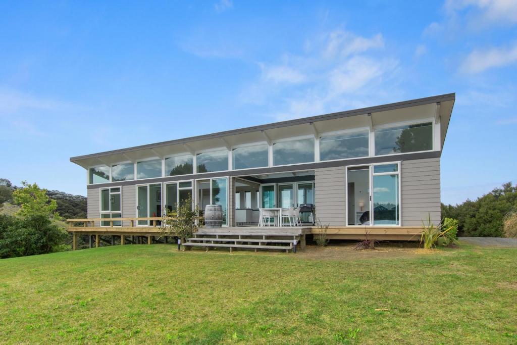 a large house with large windows on a grass field at Paroa Bay Chalets - Te Whare Kereru in Russell