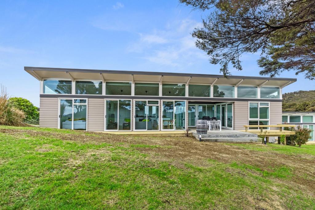 a large house with glass windows and a picnic table at Paroa Bay Chalets - Te Whare Tui in Russell