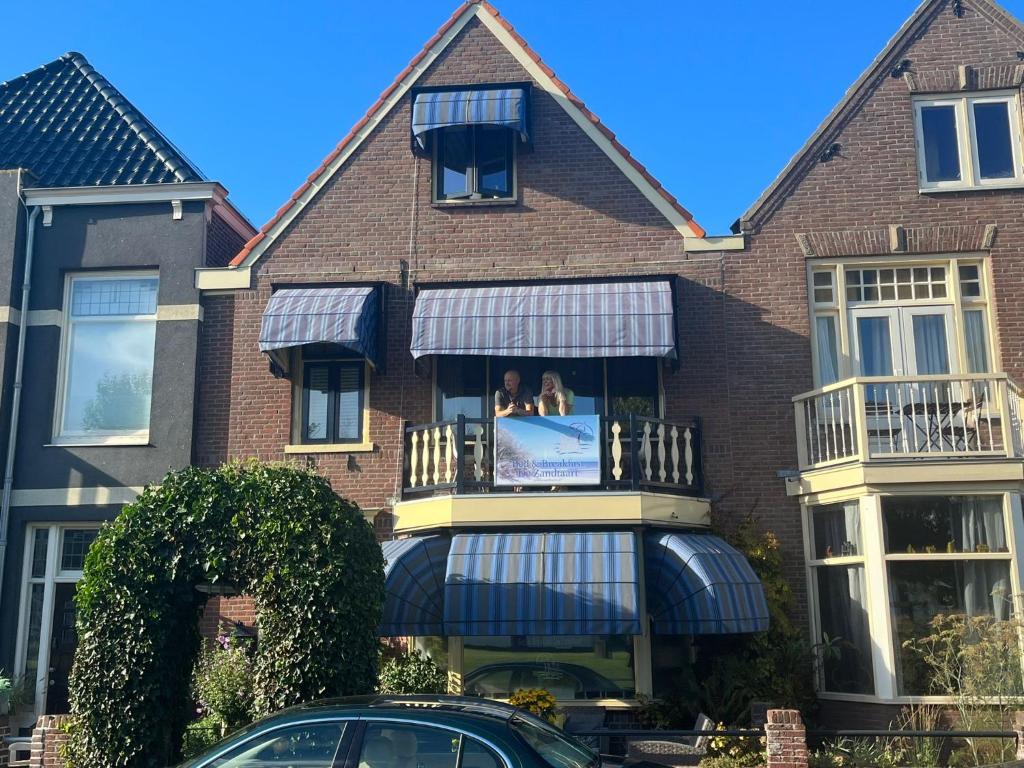 a house with a balcony with two dogs on it at B&B de Zandtaart in Egmond aan Zee
