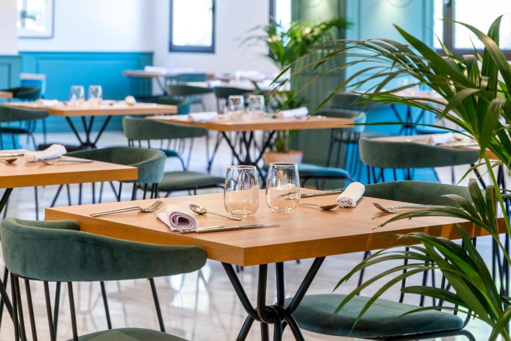 a restaurant with wooden tables and green chairs at ARTIEM Audax - Adults Only in Cala Galdana