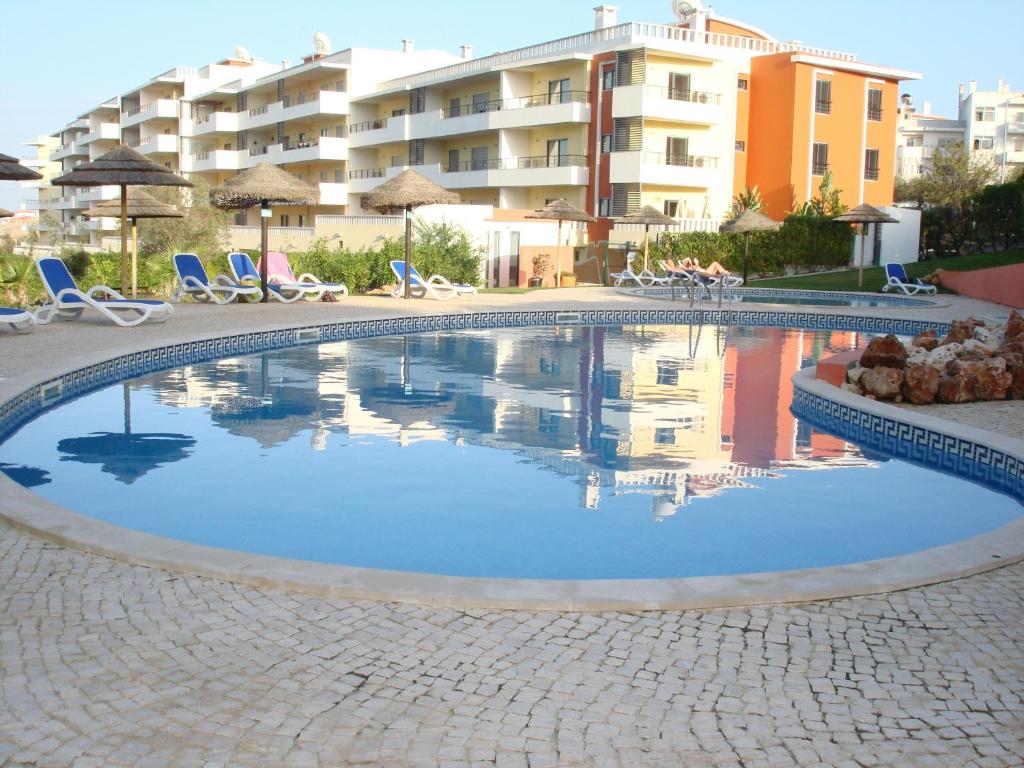 a swimming pool with chairs and a building in the background at Portugal Home in Lagos