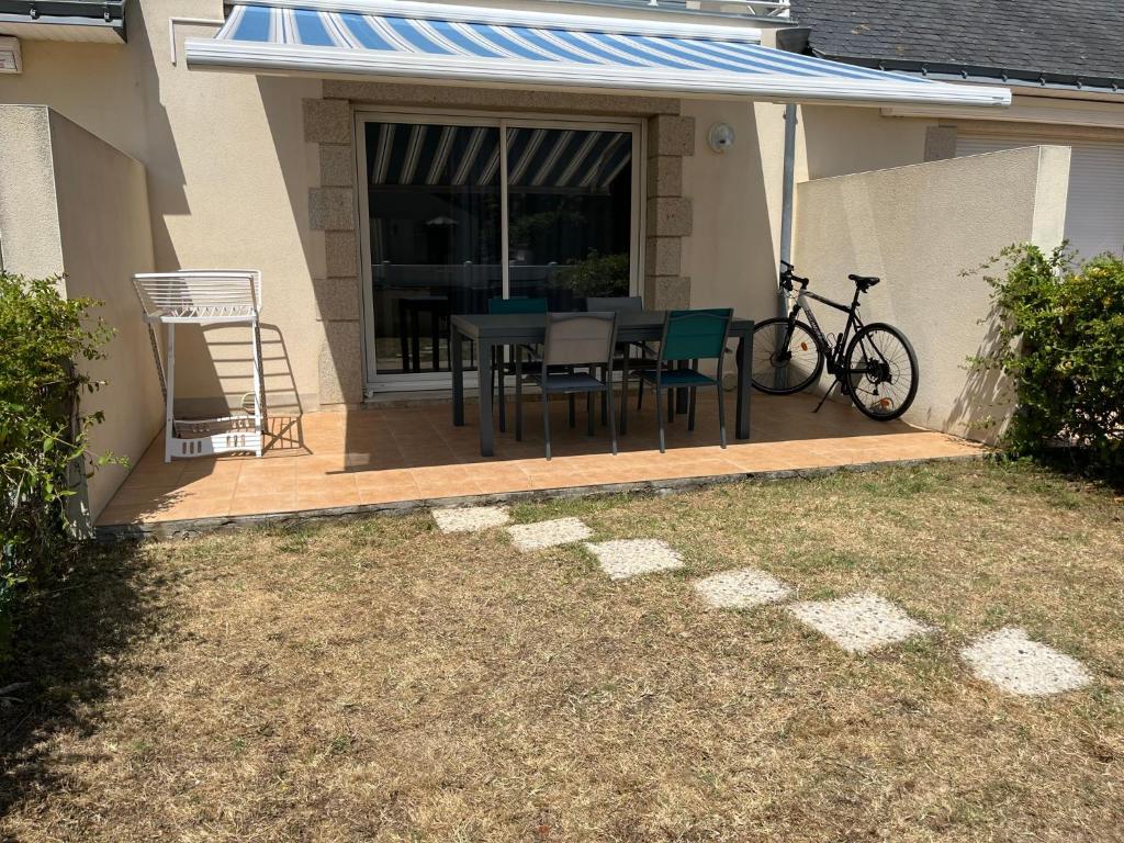 d'une terrasse avec une table, des chaises et un vélo. dans l'établissement KER LIZEA - Damgan - 4 personnes - 300 m de la grande plage, à Damgan