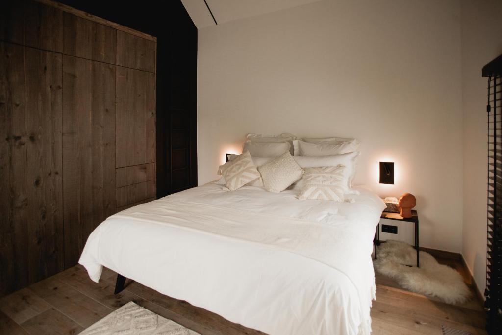 1 dormitorio con 1 cama grande con sábanas y almohadas blancas en Comme chez Lore - villa 2pers - piscine chauffée, en Namur