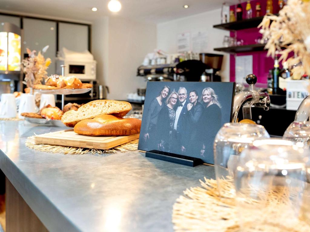 a counter with bread and a picture of the four nuns at ibis Styles Rennes St. Gregoire in Saint-Grégoire