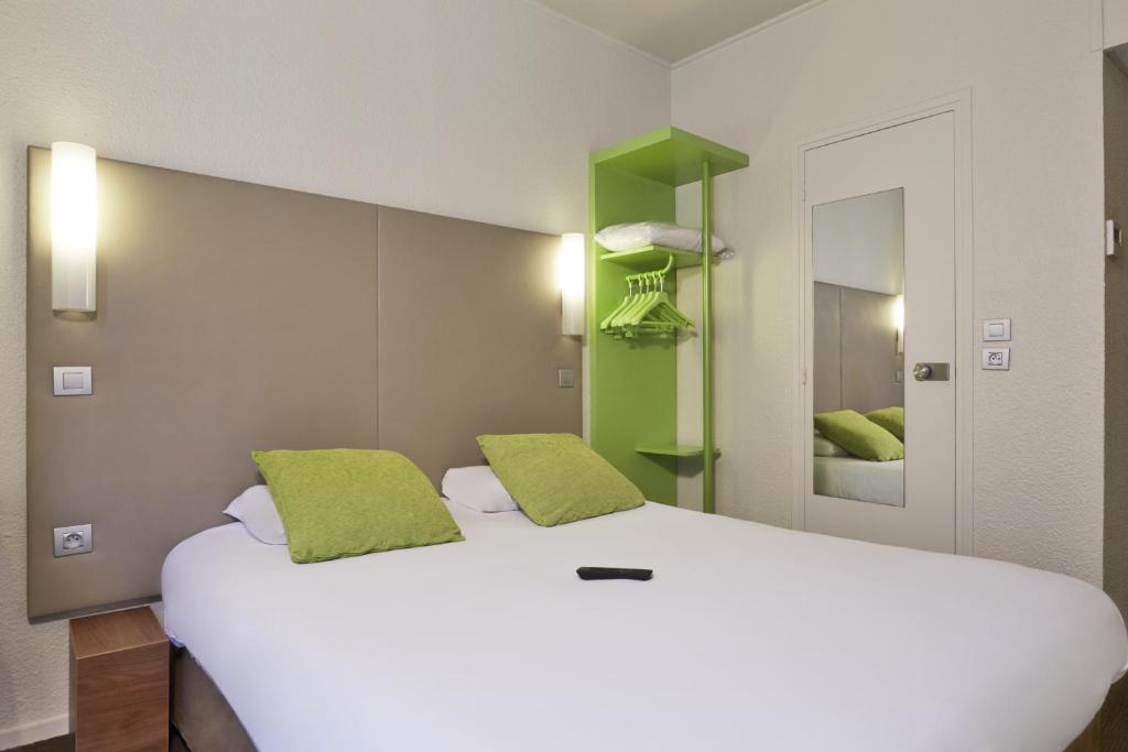 ein Schlafzimmer mit einem großen weißen Bett mit grünen Akzenten in der Unterkunft Campanile Paris Ouest - Porte de Champerret Levallois in Levallois-Perret